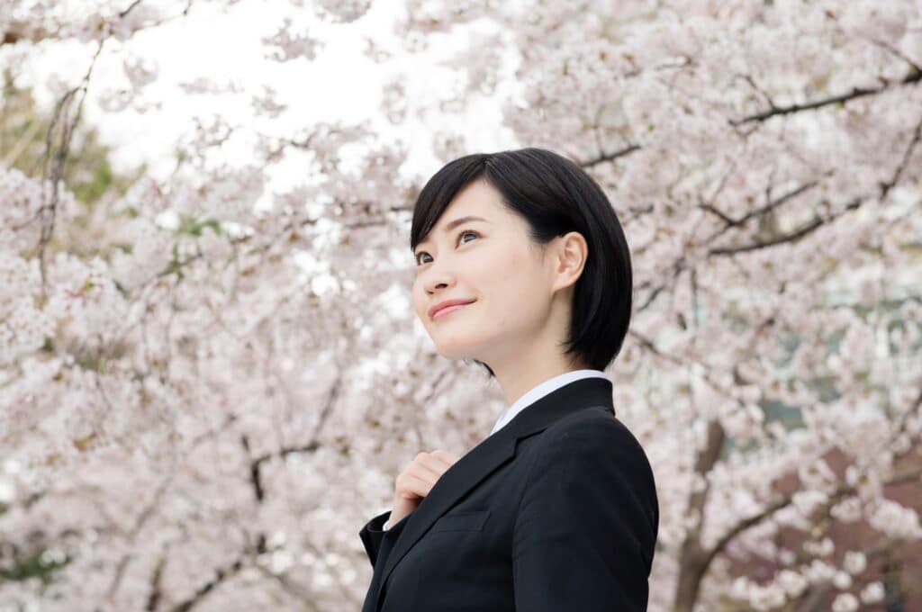 桜とスーツの女性
